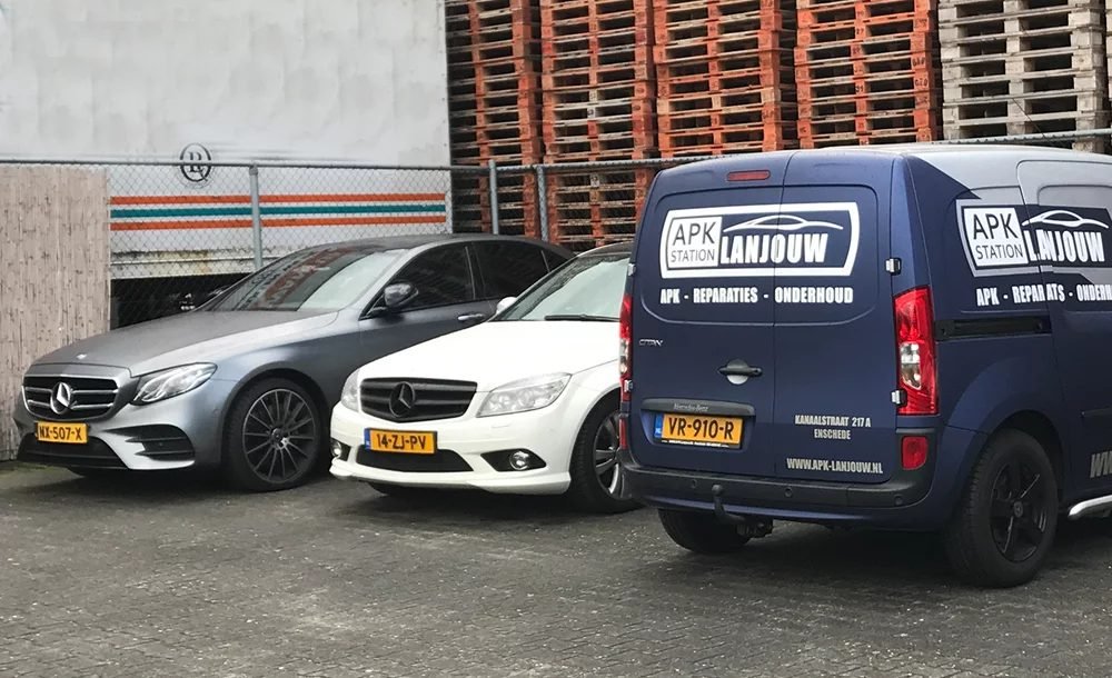 Bedrijfsbus van APK Station Lanjouw naast twee klantauto's op het terrein in Enschede